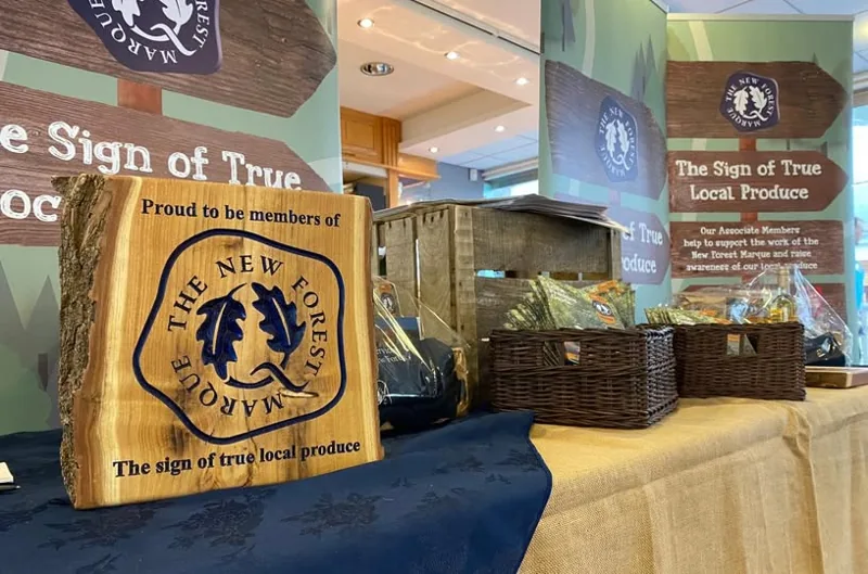 A wooden New Forest Marque plaque displayed with local produce