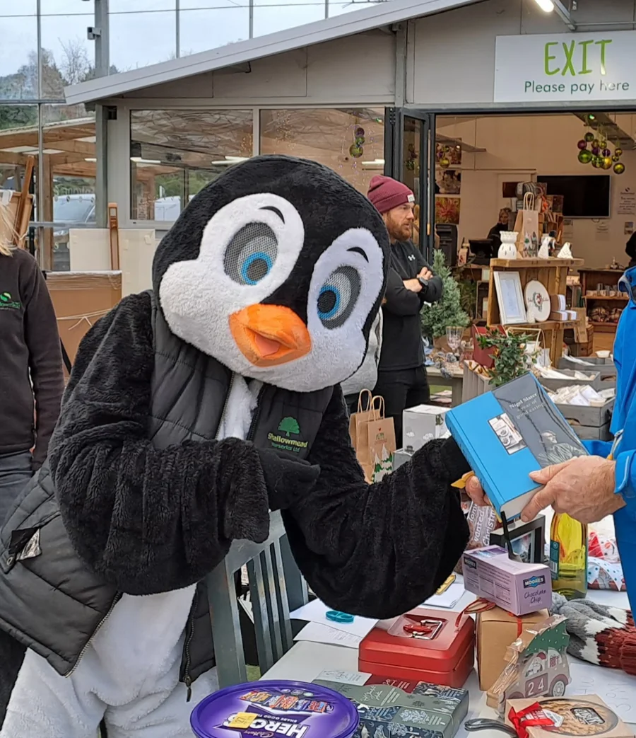 A penguin mascot at a charity stall at Shallowmead